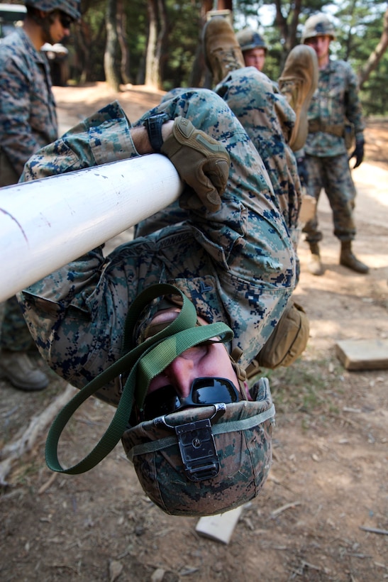 A Marine maneuvers upside down along a pole while participating in the Leadership Reaction Course at Camp Mujuk, South Korea, May 29, 2017. Marine Corps photo by Lance Cpl. Caleb T. Maher