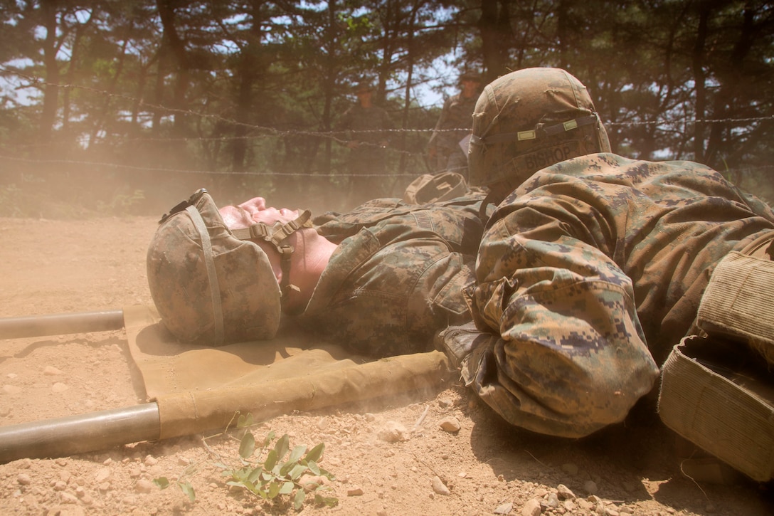 Marines and sailors move a mock casualty under a barbed wire obstacle participating in a small unit leadership building course at Camp Mujuk, South Korea, May 29, 2017. Marine Corps photo by Lance Cpl. Caleb T. Maher 