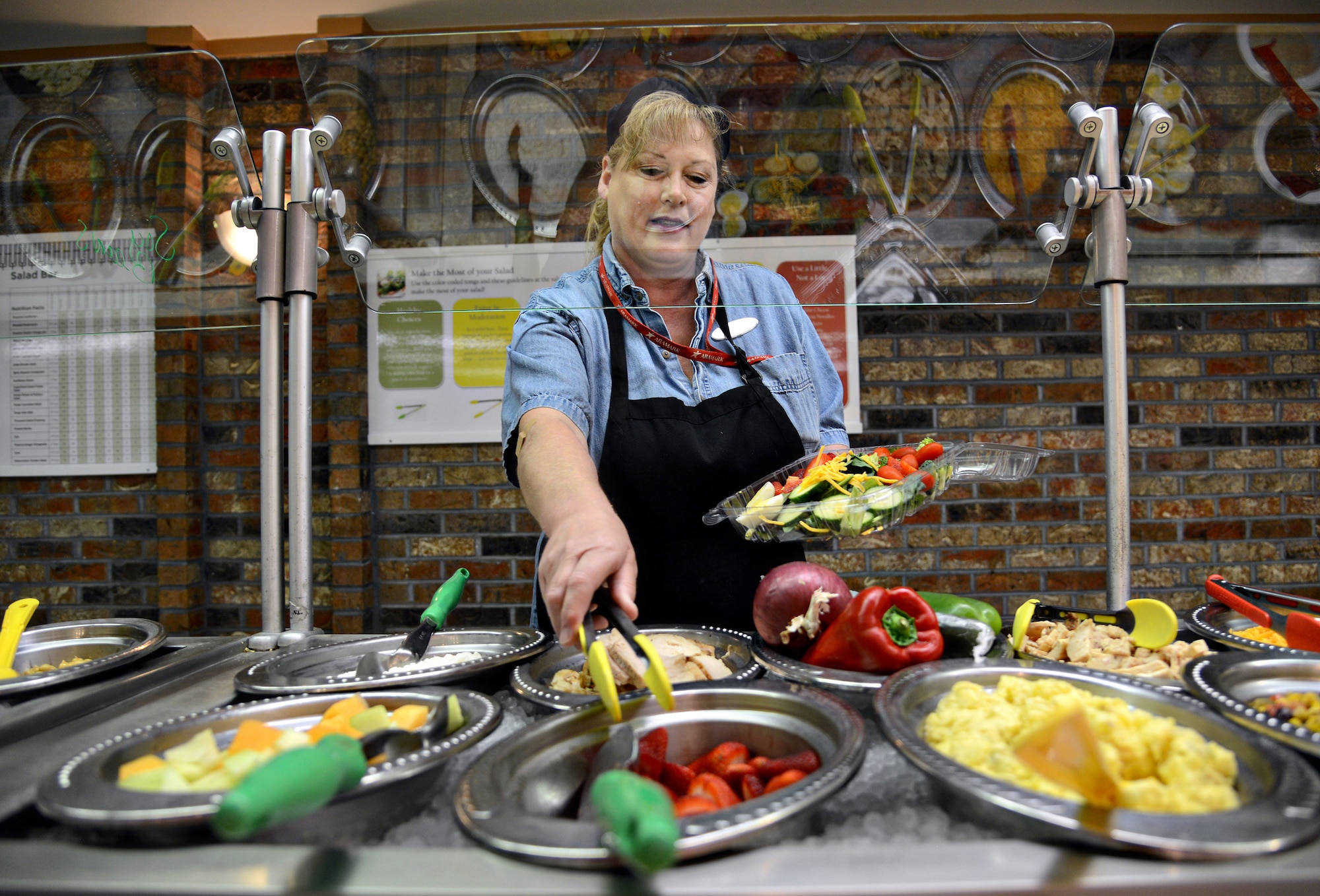 Karen Dubbe, a cashier at Cafe 3001, assembles a colorful salad for her lunch. The tongs for each food item on the salad bar have either a green, yellow or red handle, based off the "Look for the Leaf" concept for nutrition awareness, allowing the customers to be knowledgeable about healthy food selections.