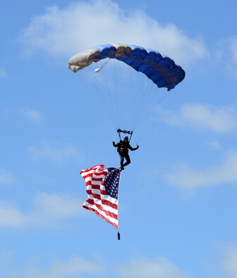 The Wings of Blue, a USAF Academy parachute team, captivated the audience with three members of the team demonstrating their precision parachute piloting skills before a fourth member gracefully glided down carrying the American Flag. (Air Force photo by Kelly White)