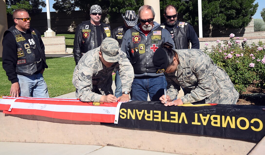 Senior Airman Chandler Baker, 377th Air Base Wing Public Affiars, and Senior Airman Karla Estrada, 377th Security Forces Squadron, sign flags at the New Mexico Veterans Memorial, May 30, 2017. The flags are being carried by members of the Combat Veterans Motorcycle Association. Two of the flags will go to each naval vessel the veterans stop at on their ride and the third will go to the association’s board of directors during the association’s annual conference. (U.S. Air Force Photo/Joanne Perkins)