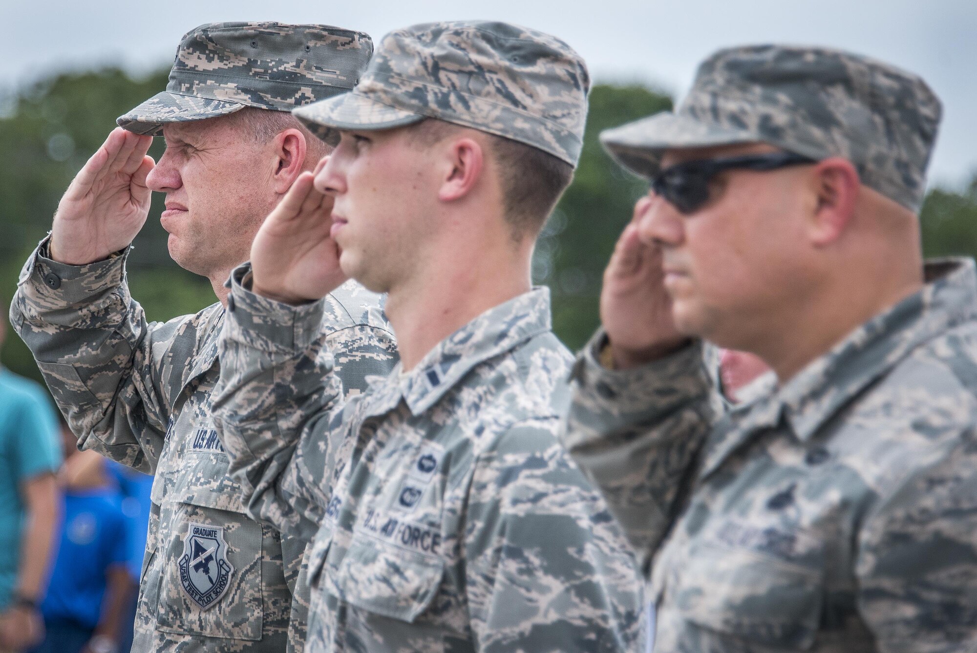 Brig. Gen. Evan Dertien, 96th Test Wing commander, 1st Lt. Lucas Huddleston, Eglin Connects coordinator, and Chief Master Sgt. Zaki Mazid, 96th TW command chief, salute during the national Anthem at the Eglin Connects event at Eglin Air Force Base, Fla., June 2.  The event to help promote resiliency featured information booths, sporting events and a car show.  (U.S. Air Force photo/Samuel King Jr.)