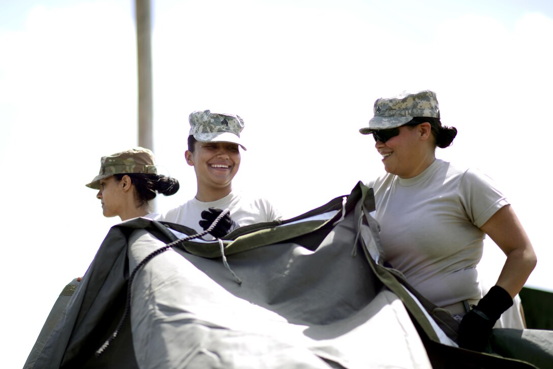 Two U.S. Army Reserve members smile as they set up a laundry tent in Paragon, Barbados, June 5, 2017. Army, Marine Corps., Navy and Coast Guard active duty and reserve members deployed to Tradewinds 2017 for a multi-national maritime security and disaster response exercise in the Caribbean. U.S. Coast Guard photo by Petty Officer 2nd Class Adam Stanton/ Released