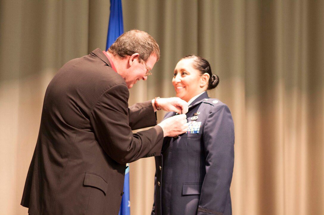 DLA Distribution Strategic Plans director Scott Rosbaugh pins the Defense Meritorious Service Medal on DLA Distribution Joint Logistic Strategic Planner Air Force Maj. Rachel Ramos.