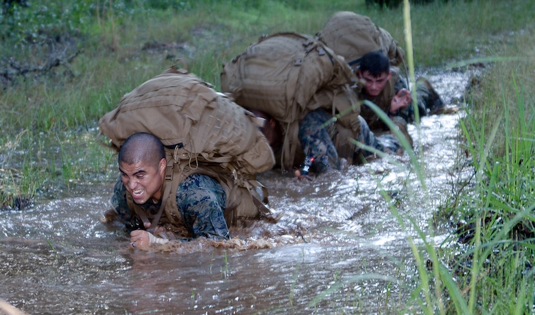 Martial arts instructor students low crawl through water during the culminating event of the Martial Arts Instructor Course aboard Marine Corps Logistics Base Albany, May 25.