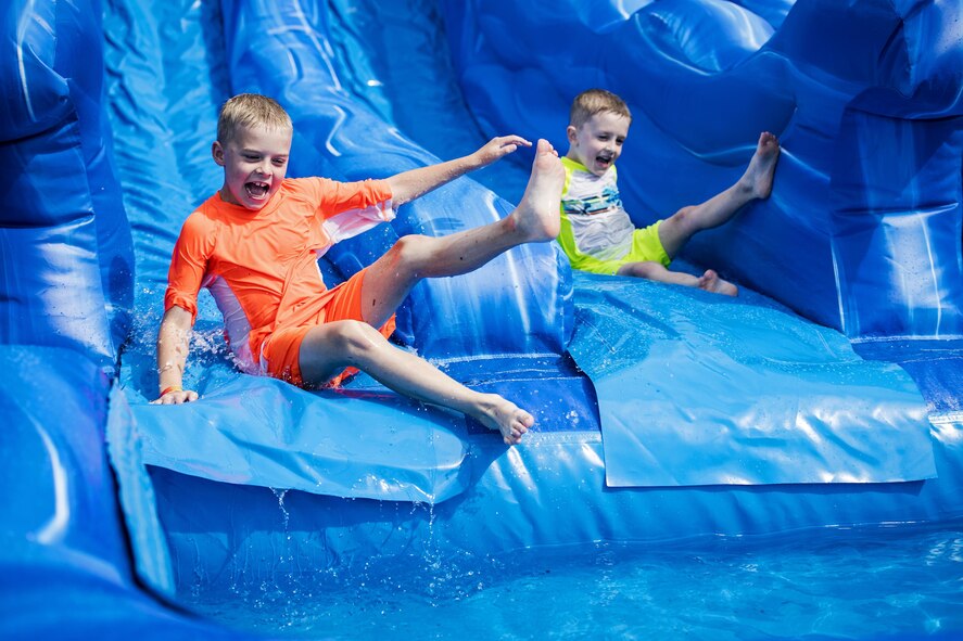 Attendees slip down a water slide during the Moody Summer Block Party, June 2, 2017, at Moody Air Force Base, Ga. Members of Team Moody were encouraged to attend the event which offered a plethora of activities for all ages, including water slides, volleyball tournaments, a car show, and live entertainment. (U.S. Air Force photo by Senior Airman Janiqua P. Robinson)