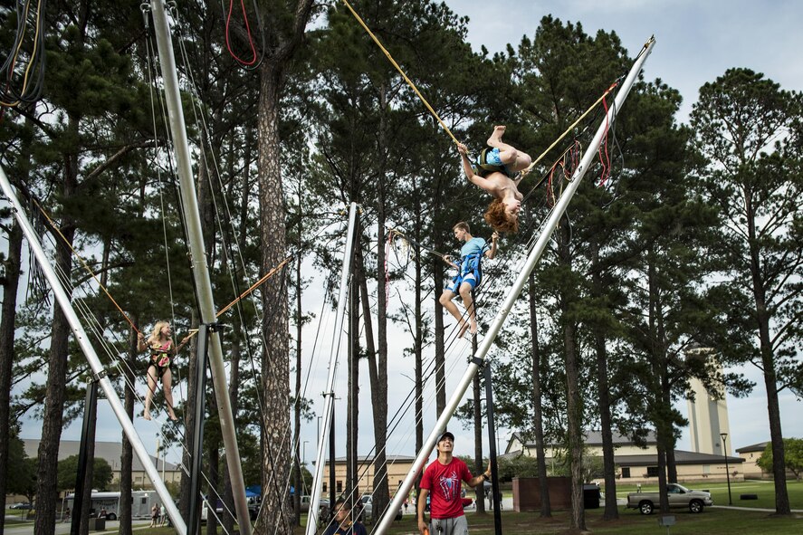 Attendees jump and flip on an attraction during the Moody Summer Block Party, June 2, 2017, at Moody Air Force Base, Ga. Members of Team Moody were encouraged to attend the event which offered a plethora of activities for all ages, including water slides, volleyball tournaments, a car show, and live entertainment. (U.S. Air Force photo by Senior Airman Janiqua P. Robinson)