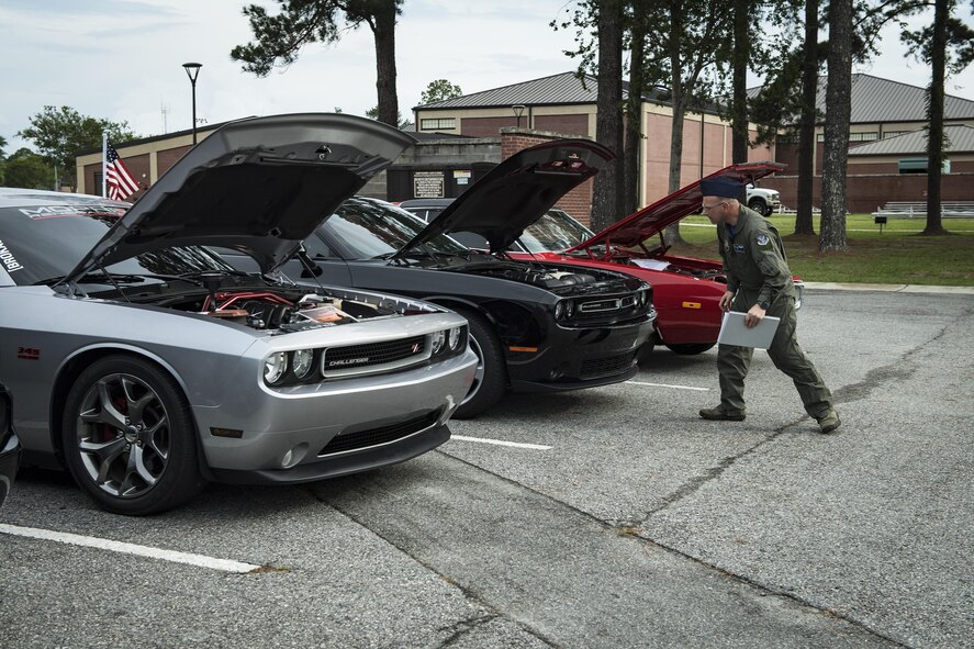 A judge looks under the hood of several cars during the car show portion of the Moody Summer Block Party, June 2, 2017, at Moody Air Force Base, Ga. Members of Team Moody were encouraged to attend the event which offered a plethora of activities for all ages, including water slides, volleyball tournaments, a car show, and live entertainment. (U.S. Air Force photo by Senior Airman Janiqua P. Robinson)