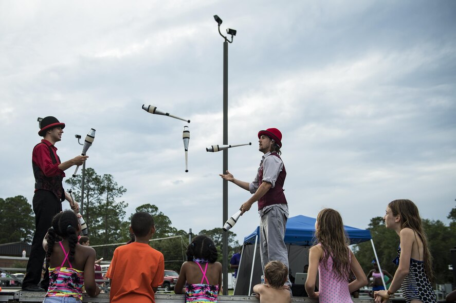 Mikhel Barkan, left, and Fred Horal, performers, juggle clubs during the Moody Summer Block Party, June 2, 2017, at Moody Air Force Base, Ga. Members of Team Moody were encouraged to attend the event which offered a plethora of activities for all ages, including water slides, volleyball tournaments, a car show, and live entertainment. (U.S. Air Force photo by Senior Airman Janiqua P. Robinson)