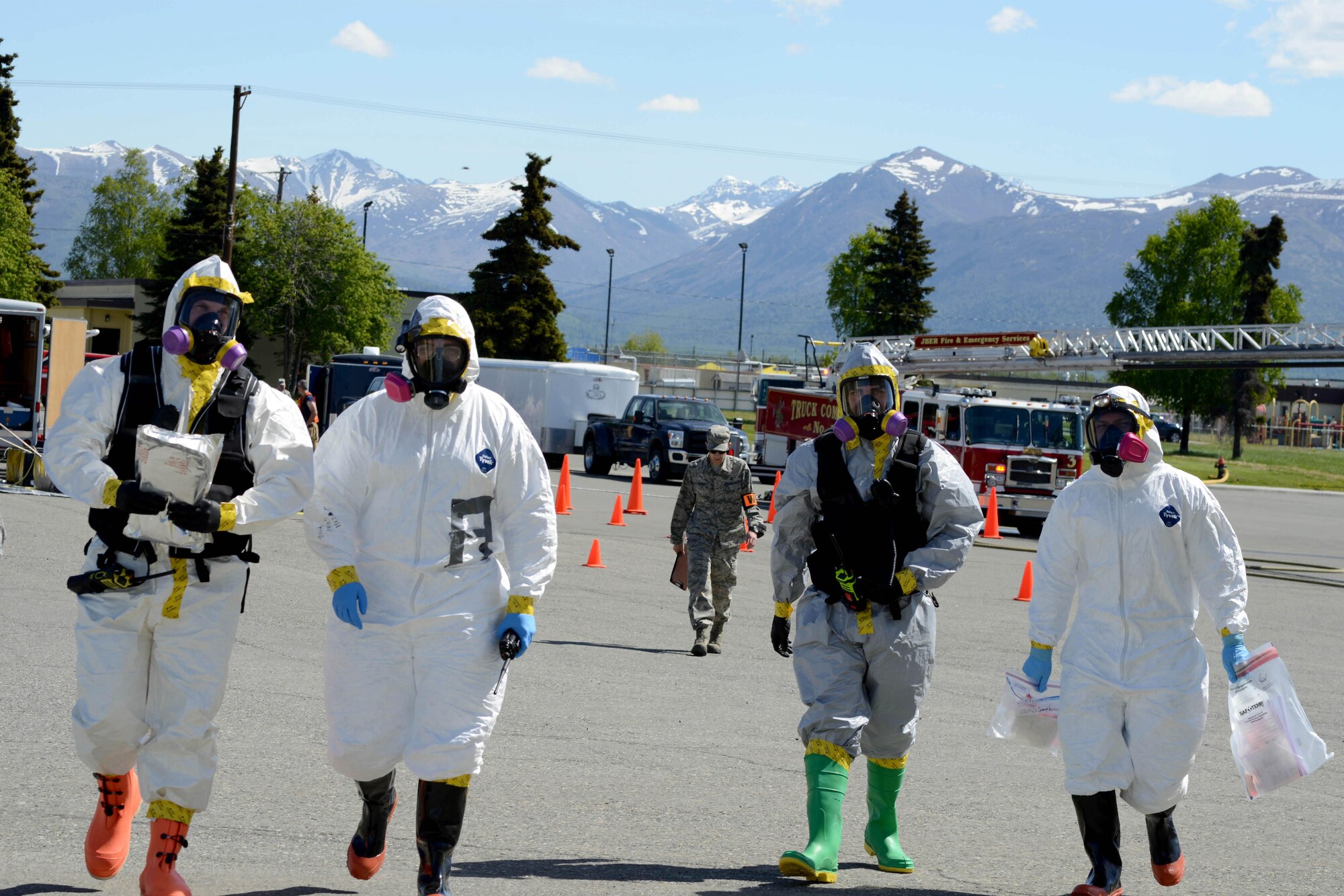 Airmen of the 673d Aerospace Medical Squadron in their hazardous material suits make their way toward the Talkeetna Theater during a Mission Assurance Exercise, June 1, 2017. The exercise tested the installation’s capabilities in dealing with a simulated anthrax attack.
