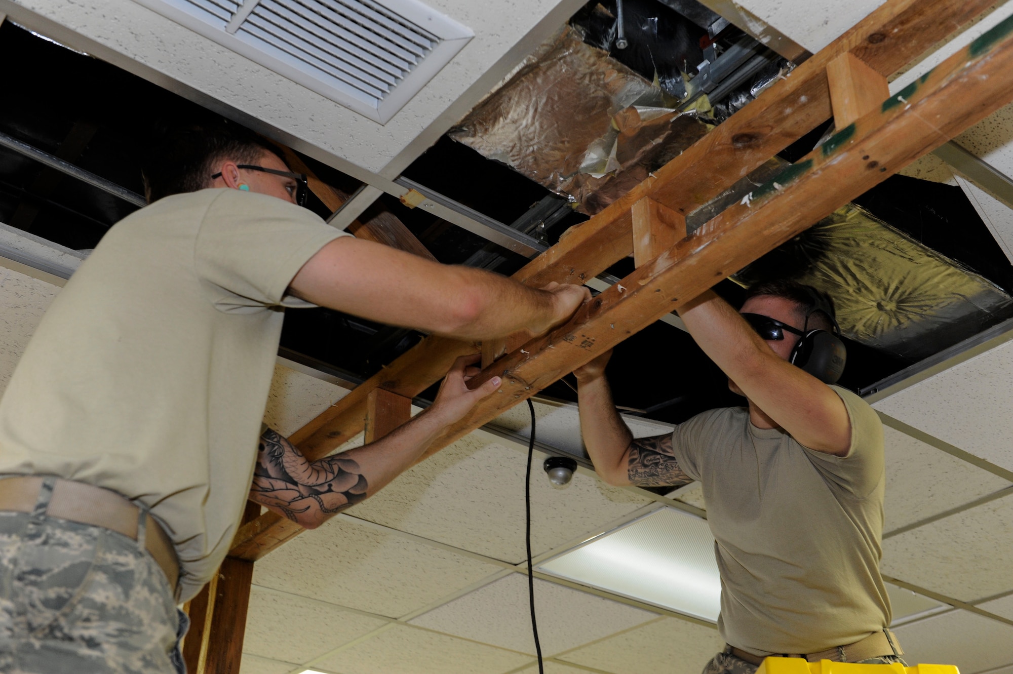 U.S. Air Force Airman 1st Class Kaden Petersen, 18th Civil Engineer Squadron structural apprentice and Senior Airman Devin Curtman, 18th CES structural journeyman, remove a wall frame from ceiling bearings at the 961st Airborne Air Control Squadron May 17, 2017, at Kadena Air Base, Japan. The 18th CES Structures Airmen conduct maintenance on Kadena’s buildings, ensuring they meet safety and maintenance standards. (U.S. Air Force photo by Senior Airman Lynette M. Rolen)