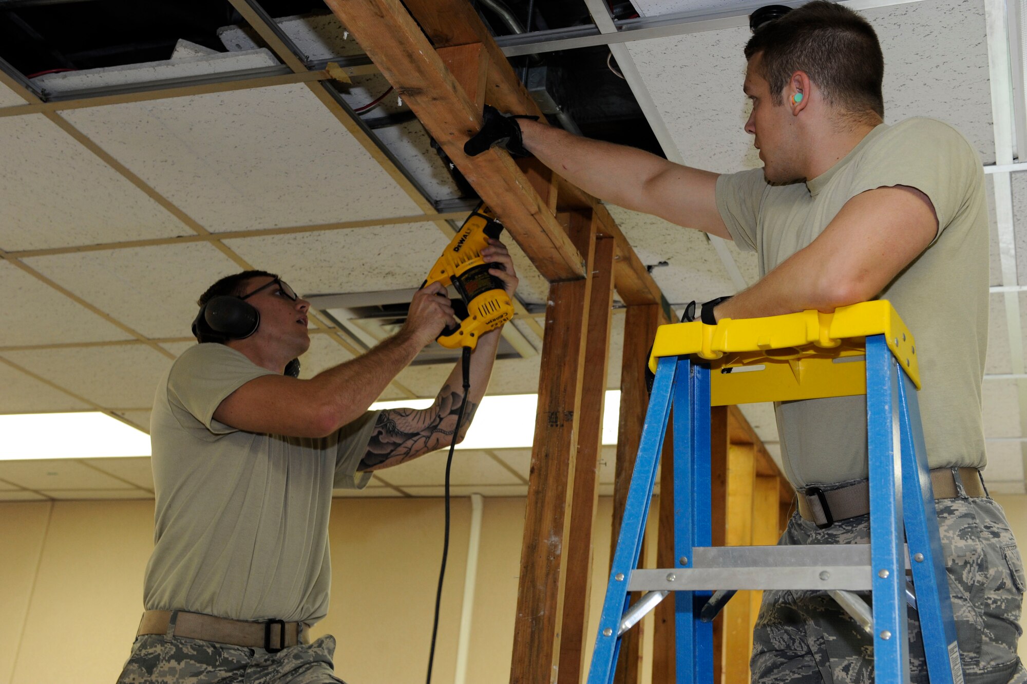 U.S. Air Force Airmen 1st Class Kaden Petersen and Joseph Carswell, 18th Civil Engineer Squadron structural apprentices, take down the top part of a wall frame at the 961st Airborne Air Control Squadron May 17, 2017, at Kadena Air Base, Japan. The 18th CES structures Airmen ensure buildings are mission-capable at all times. Projects to ensure this include making more space for units to hold mission meetings.  (U.S. Air Force photo by Senior Airman Lynette M. Rolen)