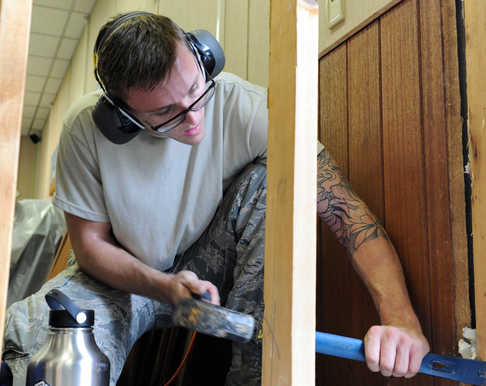 U.S. Air Force Airman 1st Class Kaden Petersen, 18th Civil Engineer Squadron structures apprentice, removes a nail from a wall frame as part of a workspace expansion project at the 961st Airborne Air Control Squadron May 17, 2017, at Kadena Air Base, Japan. Proper use of individual protective equipment, such as hearing protection, is vital to individual safety. (U.S. Air Force photo by Senior Airman Lynette M. Rolen)