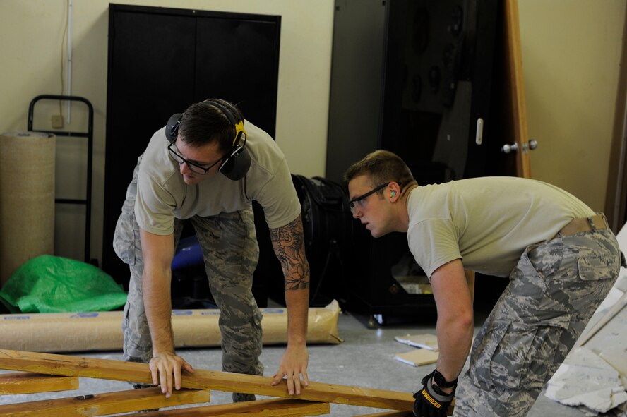 U.S. Air Force Airmen 1st Class Kaden Petersen and Joseph Carswell, 18th Civil Engineer Squadron structural apprentices, lay down part of a wall frame as part of a workspace expansion project at the 961st Airborne Air Control Squadron May 17, 2017, at Kadena Air Base, Japan. Using proper safety techniques for moving equipment and materials is important for prevention of workplace injuries. (U.S. Air Force photo by Senior Airman Lynette M. Rolen)