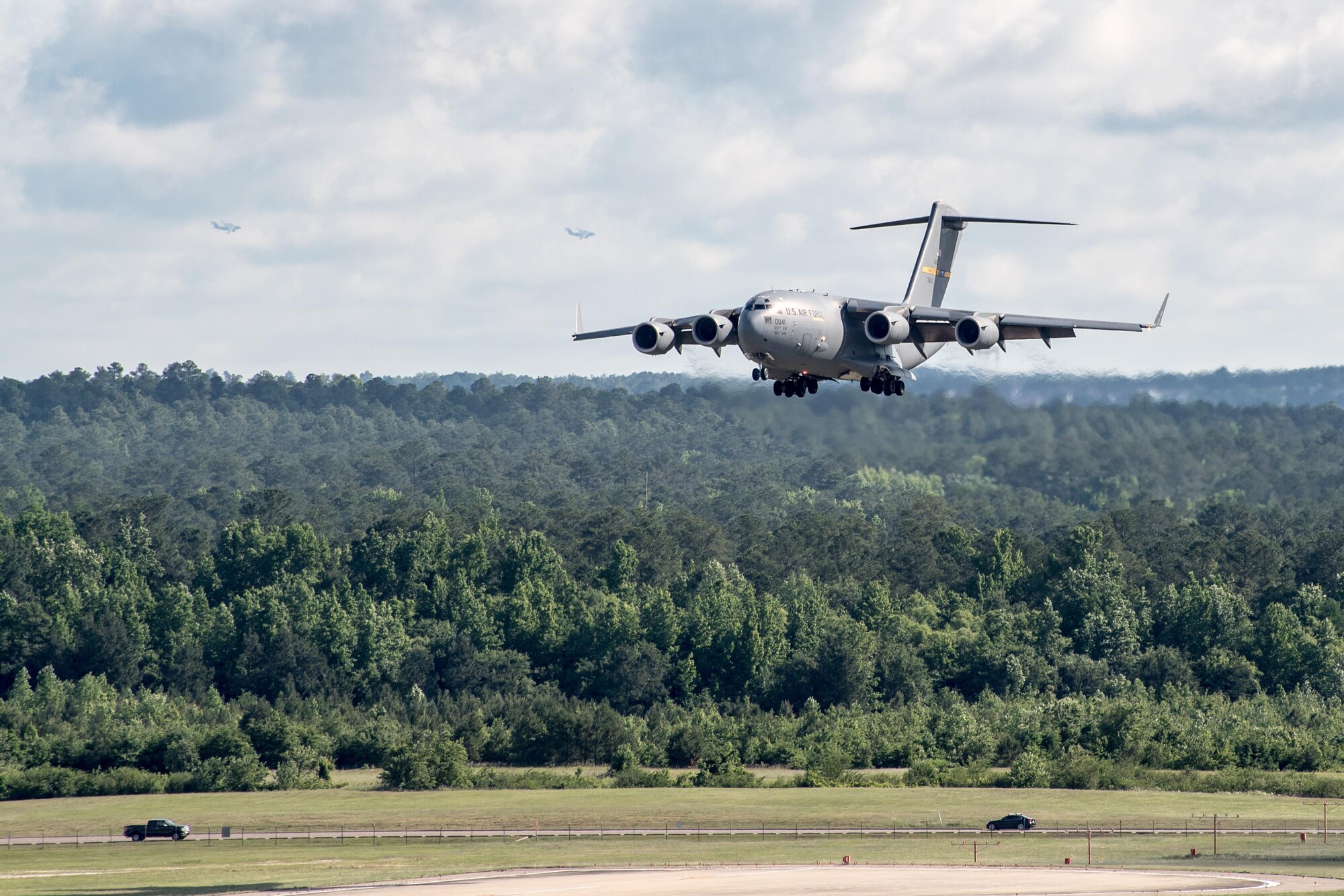 POPE ARMY AIRFIELD, N.C. -- A C-17 Globemaster III from the 437th Airlift Wing at Joint Base Charleston, S.C., prepares to land here as two additional Globemasters circle around for a landing in the background. The 43d Air Mobility Operations Group here supported the Army's 82nd Airborne Division and visiting Air Mobility Command aircrews as they prepared for the annual All American Week airdrop at Sicily Drop Zone on Fort Bragg. The drop was cancelled due to weather after launching from Pope Field. (U.S. Air Force photo/Marc Barnes)
