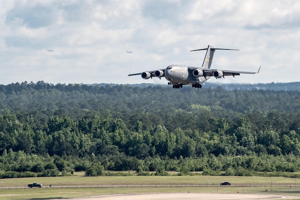 POPE ARMY AIRFIELD, N.C. -- A C-17 Globemaster III from the 437th Airlift Wing at Joint Base Charleston, S.C., prepares to land here as two additional Globemasters circle around for a landing in the background. The 43d Air Mobility Operations Group here supported the Army's 82nd Airborne Division and visiting Air Mobility Command aircrews as they prepared for the annual All American Week airdrop at Sicily Drop Zone on Fort Bragg. The drop was cancelled due to weather after launching from Pope Field. (U.S. Air Force photo/Marc Barnes)
