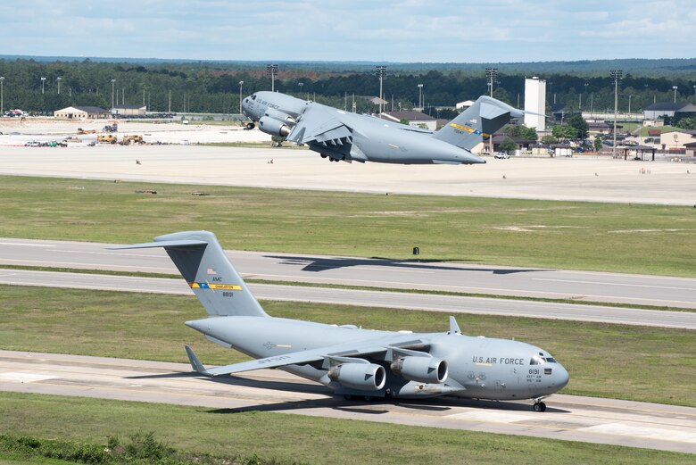 POPE ARMY AIRFIELD, N.C. -- A C-17 Globemaster III from the 437th Airlift Wing at Joint Base Charleston, S.C., launches from the runway here as another taxis for takeoff May 25 during the 82nd Airborne Division's All American Week. The 43d Air Mobility Operations Group supported the 82nd and visiting Air Mobility Command aircrews as they prepared for the annual All American Week airdrop at Sicily Drop Zone on Fort Bragg. The drop was cancelled due to high winds after the aircraft launched from Pope Field. (U.S. Air Force photo/Marc Barnes)