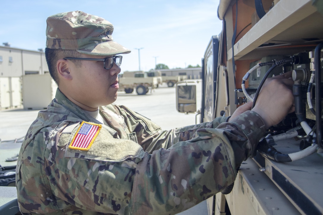 Army Spc. Jesse Thepouhthay, an air traffic control equipment repairer assigned to Foxtrot Company, 6th Battalion, 101st General Support Aviation Battalion, at Fort Campbell, Ky., checks a vehicle in the motor pool, May 16, 2017. Thepouhthay's role model is his father, who immigrated to America from Laos. Army photo by Leejay Lockhart