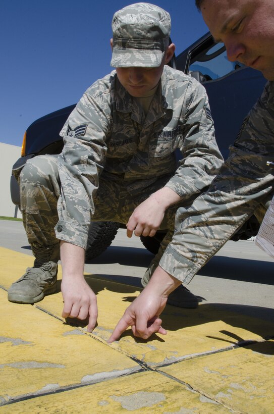 SrA Mike Vasilakos Engineering Assistant, 108th Civil Engineer Squadron, and Tech. Sgt. Sean Joseph, Operations Manager, 108th Civil Engineer Squadron, inspect and document a crack in the cement of the 108th aircraft parking ramp that without proper maintenance has the potential to create FOD (foreign object debris) and damage an aircraft. (U.S. Air National Guard photo by Staff Sgt. Ross A. Whitley/Released)