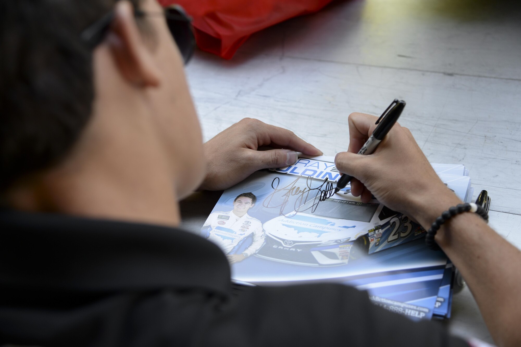 Gray Gaulding, driver of the No. 23 car, signs an autograph during the biannual NASCAR Social June 2, 2017, at Dover Air Force Base, Del. Gray and several other NASCAR drivers visited the free event to show support for the military families there. (U.S. Air Force photo by Senior Airman Aaron J. Jenne)