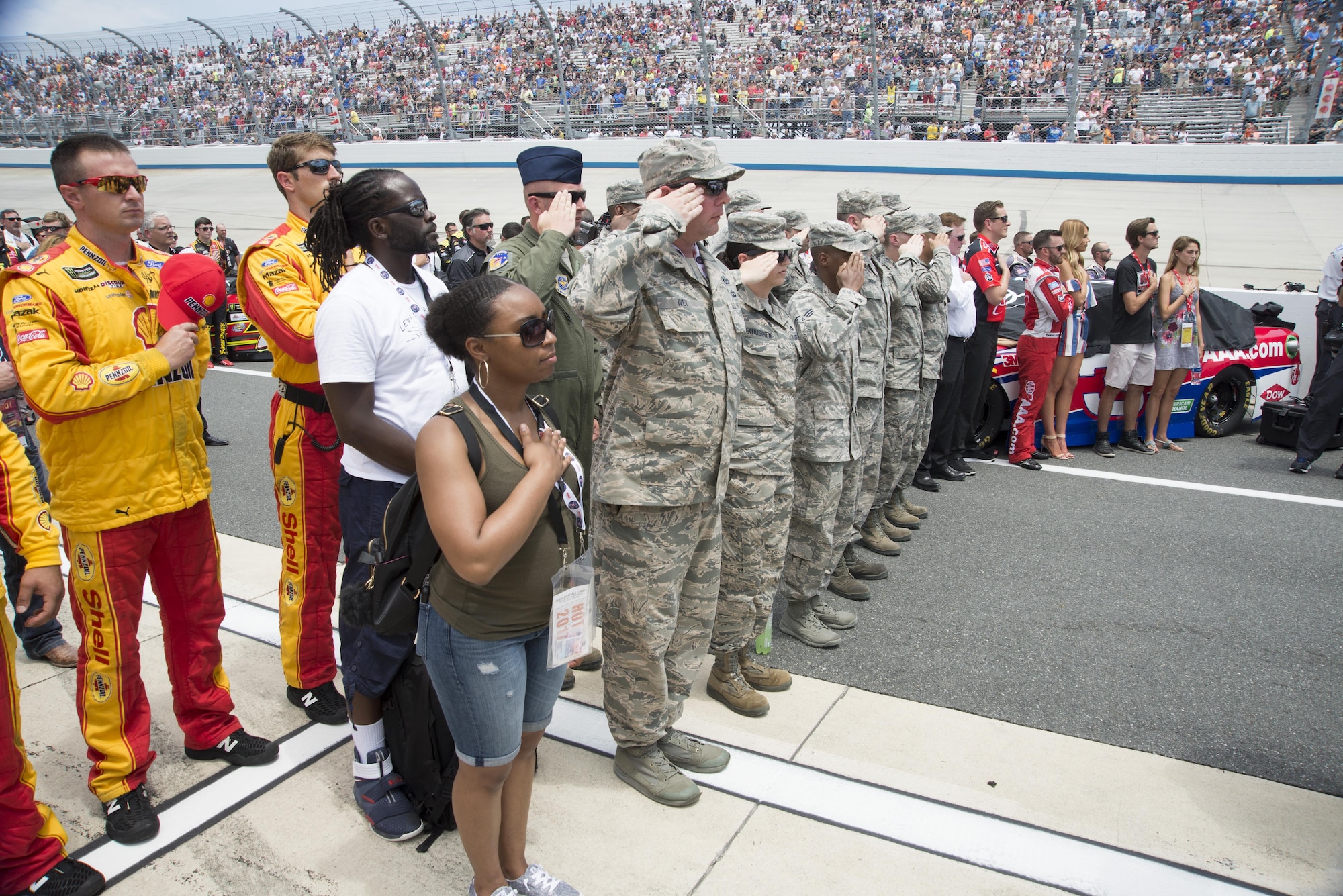 Team Dover members salute during the playing of the National Anthem before the start of the AAA 400 Drive for Autism Monster Energy race June 4, 2017, at Dover International Speedway, Dover, Del. They were a part of the honorary pit crew member program, which provides Airmen the opportunity to interact with the drivers and pit crew members at the race. (U.S. Air Force photo by Staff Sgt. Jared Duhon)
