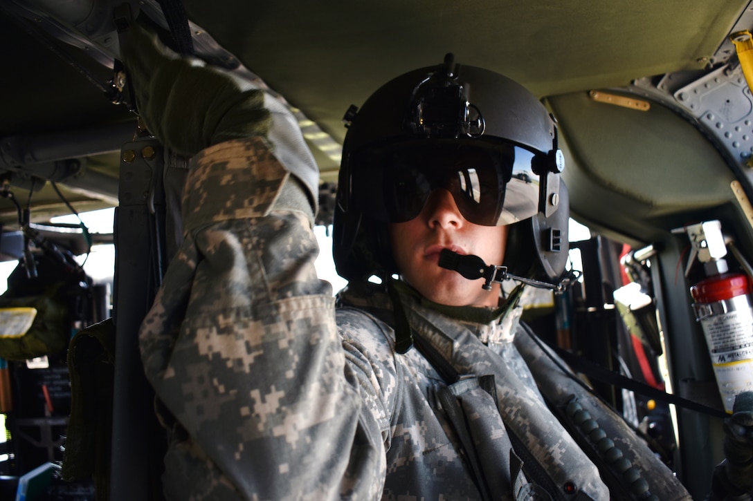 Army Sgt. John Grassia checks the radio in a UH-60 Black Hawk helicopter at an Army aviation facility in Latham, N.Y., May 31, 2017. Grassia, a crew chief assigned to the New York Army National Guard’s 3rd Battalion, 142nd Aviation Regiment, participated in bucket firefighting system training. Army National Guard photo by Pfc. Andrew Valenza
