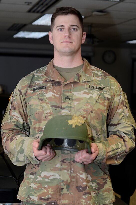 Army Sgt. Matthew Waymire holds his damaged Kevlar helmet at his desk at the Defense Information School on Fort Meade, Md., May 31, 2017. He wore the helmet in Afghanistan, where he suffered a bullet wound to the head in 2006. 