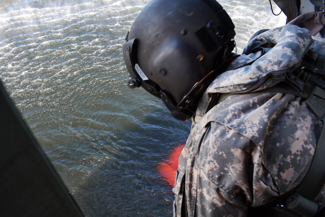 A New York Army National Guardsman in a UH-60 Black Hawk helicopter watches a bucket firefighting system fill with water during training near Round Lake, N.Y., May 31, 2017. Army National Guard photo by Pfc. Andrew Valenza
