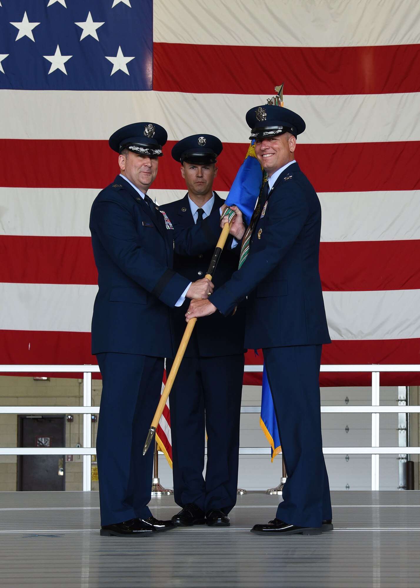 Maj. Gen. Christopher Bence, U.S. Air Force Expeditionary Center commander, left, passes the guidon to the new commander of the 319th Air Base Wing, Col. Benjamin Spencer, right, at an assumption of command ceremony June 6, 2017, on Grand Forks Air Force Base, N.D. Spencer is transitioning from Davis-Monthan Air Force Base, N.M., with his wife, Beth, and son, Evan. (U.S. Air Force photo by Airman 1st Class Elora McCutcheon)