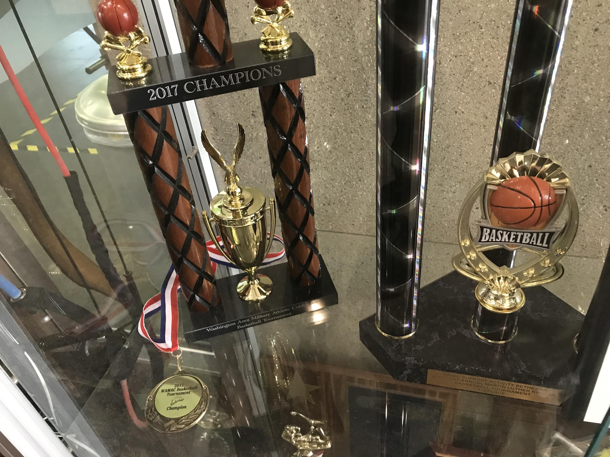 Trophies and a medal won by the Joint Base Langley-Eustis, Men’s Varsity basketball team, the “Raptors,” is displayed in the Shellbank Fitness Center at Joint Base Langley-Eustis, Va., June 6, 2017. The Raptors finished the season with eight regular season wins, two third place wins and one first place tournament finish. (Courtesy Photo)