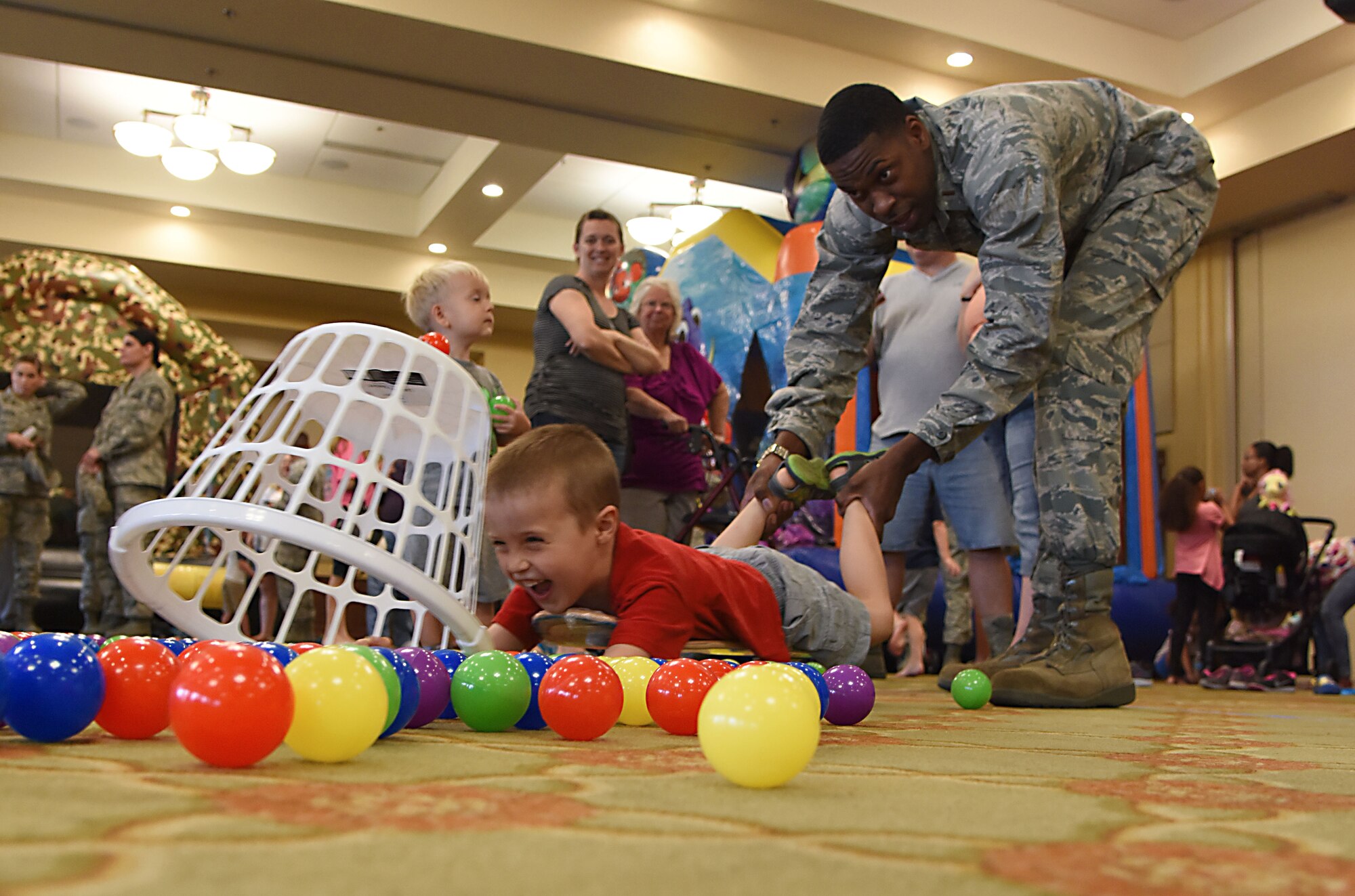 Second Lt. Jared Hines, 81st Contracting Squadron contract specialist, assists Oliver Weller, son of Staff Sgt. Patrick Weller, 333rd Training Squadron instructor, with capturing plastic balls with a basket during the Keesler Summer Bash at the Bay Breeze Event Center June 1, 2017, on Keesler Air Force Base, Miss. The bash consisted of demonstrations by the 338th TRS drill team and the 81st Security Forces Squadron military working dogs, games and free food. (U.S. Air Force photo by Kemberly Groue)