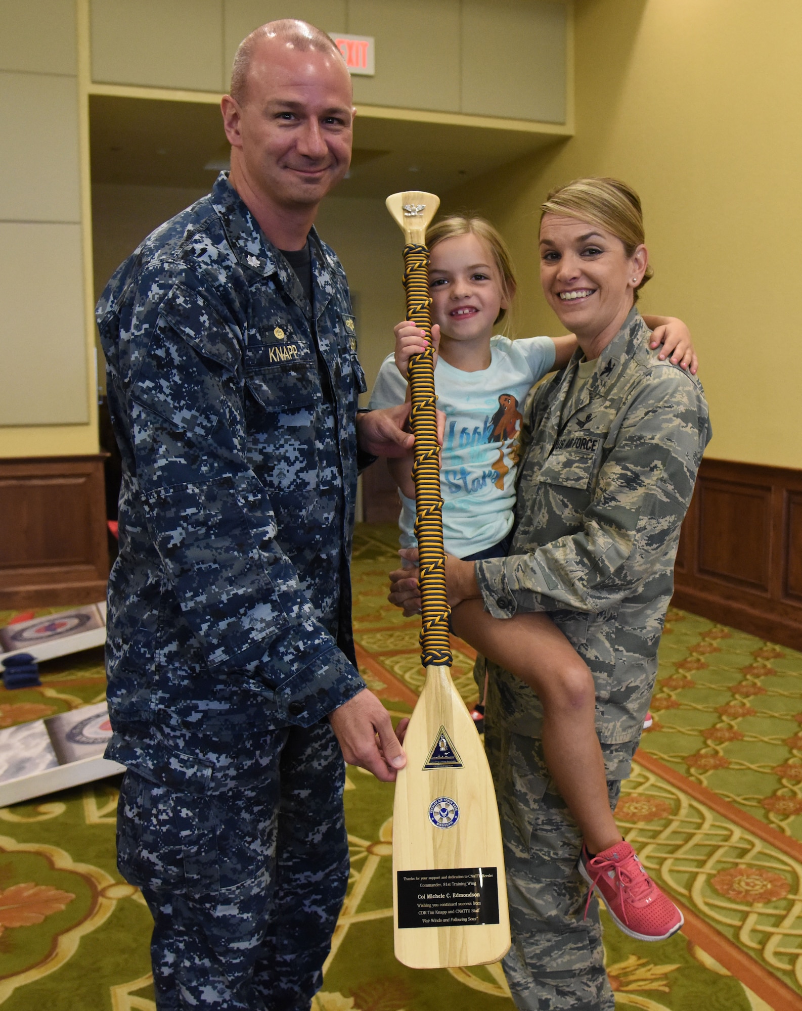 U.S. Navy Cmdr. Timothy Knapp, Center for Naval Aviation Technical Training Unit Keesler commanding officer, presents Col. Michele Edmondson, 81st Training Wing commander, and her daughter, Jacqueline, joins her during the Keesler Summer Bash at the Bay Breeze Event Center June 1, 2017, on Keesler Air Force Base, Miss. The bash consisted of demonstrations by the 338th Training Squadron drill team and the 81st Security Forces Squadron military working dogs, games and free food. (U.S. Air Force photo by Kemberly Groue)