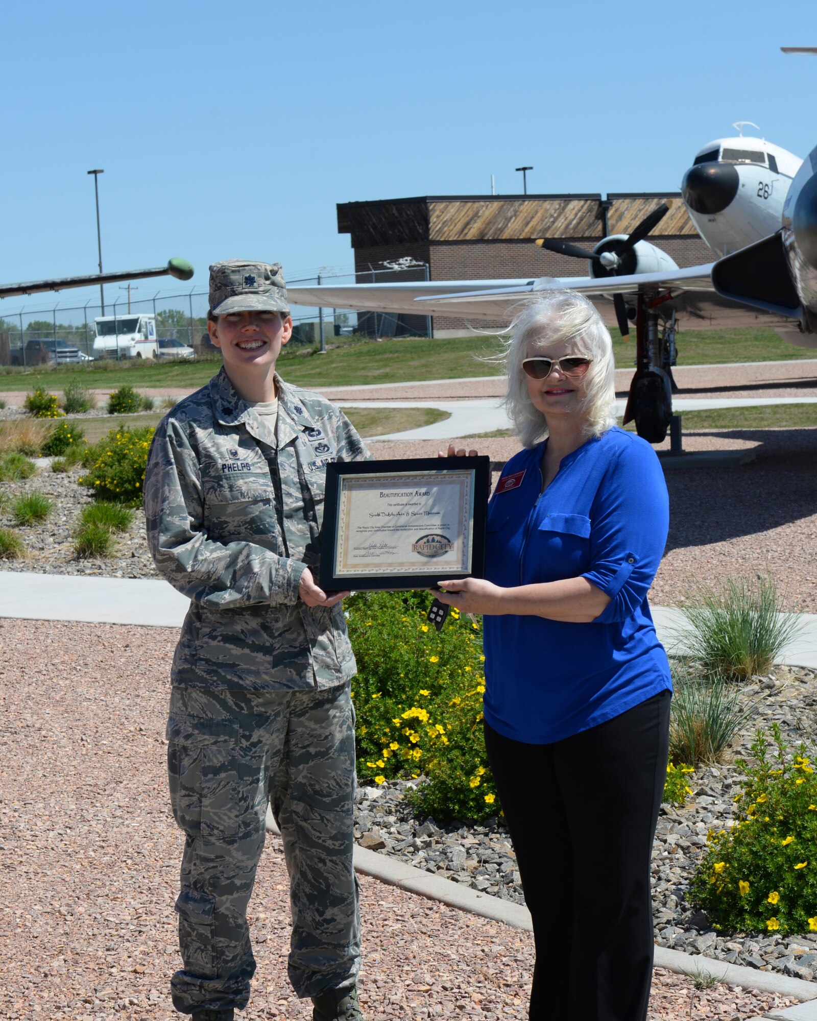 Lt. Col. Jennifer Phelps, commander of the 28th Civil Engineer Squadron, accepts the June 2017 Beautification and Revitalization Award from Vesta Wells Johnson, chairman of the beautification committee of the Rapid City Area Chamber of Commerce, at the South Dakota Air and Space Museum in Box Elder, S.D., May 31, 2017. The award is presented to a local business or agency that has completed projects that enhance the beauty of Rapid City. (U.S. Air Force photo by Airman Nicolas Z. Erwin)