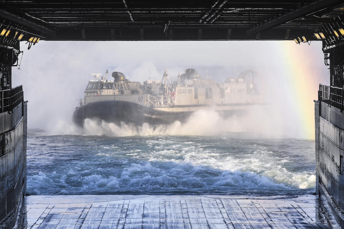 A Navy air-cushion landing craft departs the well deck of a ship.