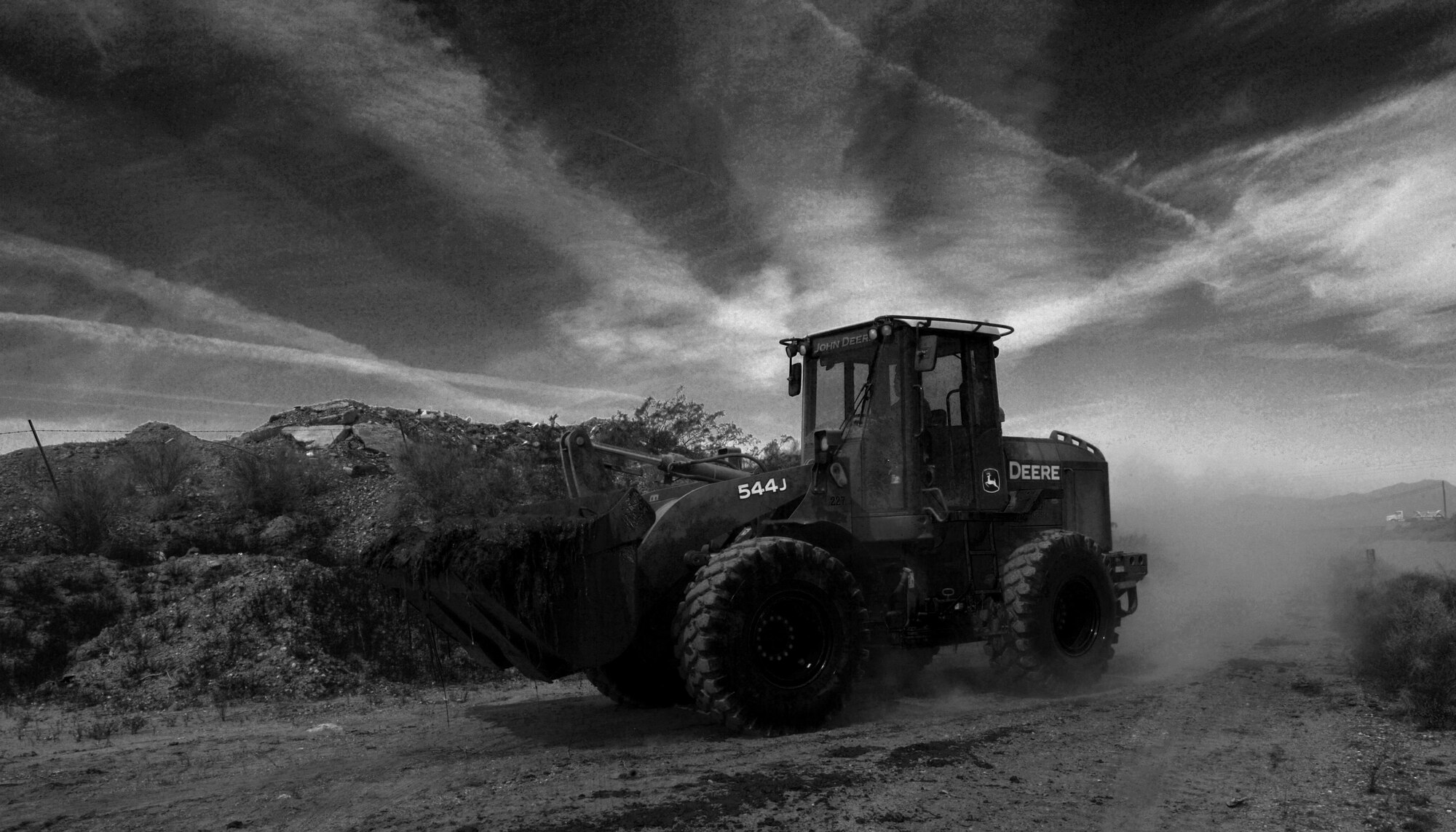 A loader carries a bucket full of sludge May 30, 2017 in Glendale, Az. Airmen from seven bases across the country partnered with Luke Air Force Base for the annual Bird/Wildlife Air Strike Hazard project to clear away more than 1000 tons of mud, vegetation and debris from around the perimeter of the base to deter the local bird and wildlife population and keep the airfields safe. (U.S. Air Force photo by Staff Sgt. Marcy Copeland)