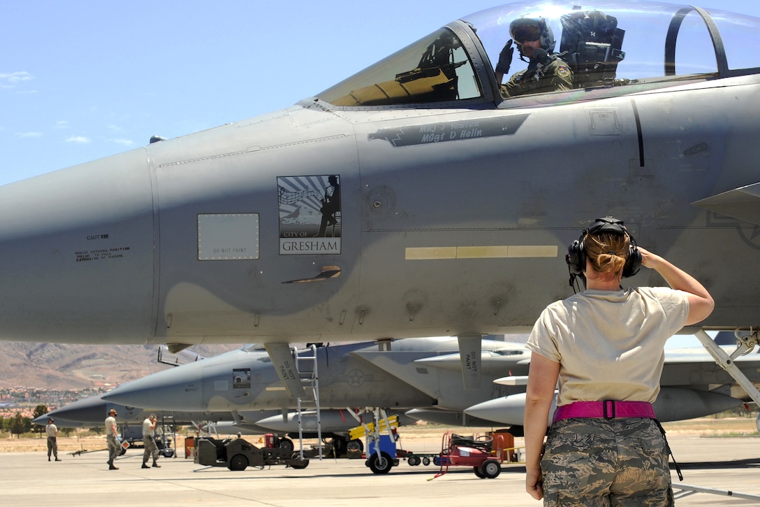 Oregon Air National Guard Senior Airman Aimee Lonidier, foreground, salutes Capt. Jamie Hastings as he prepares to take off for a sortie at Nellis Air Force Base, Nev., June 1, 2017. Lonidier is a crew chief assigned to the 142nd Fighter Wing Maintenance Group. Hastings is a pilot assigned to the 123rd Fighter Squadron. Air National Guard photo by Master Sgt. John Hughel