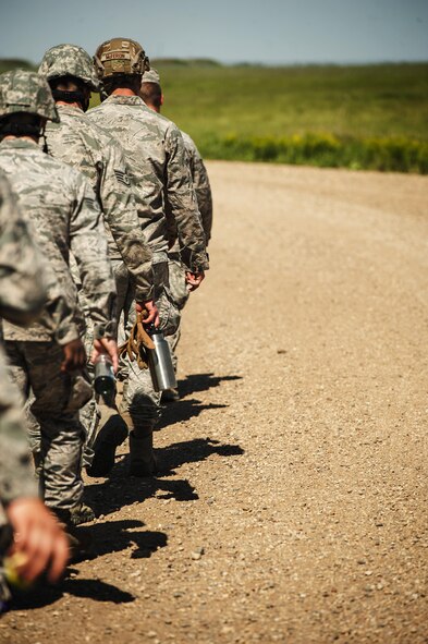 Airman from the 5th Civil Engineer Squadron walk down a dirt road looking for simulated improvised explosive devices during an Expeditionary Training Day at Minot Air Force Base, N.D., June 1, 2017. The day consisted of a “bag drag” and 6-mile ruck march, followed by tent set-up, rappelling, helicopter hoists, search-and-rescue training, convoy operations and Self-Aid and Buddy Care. (U.S. Air Force photo/Senior Airman J.T. Armstrong)