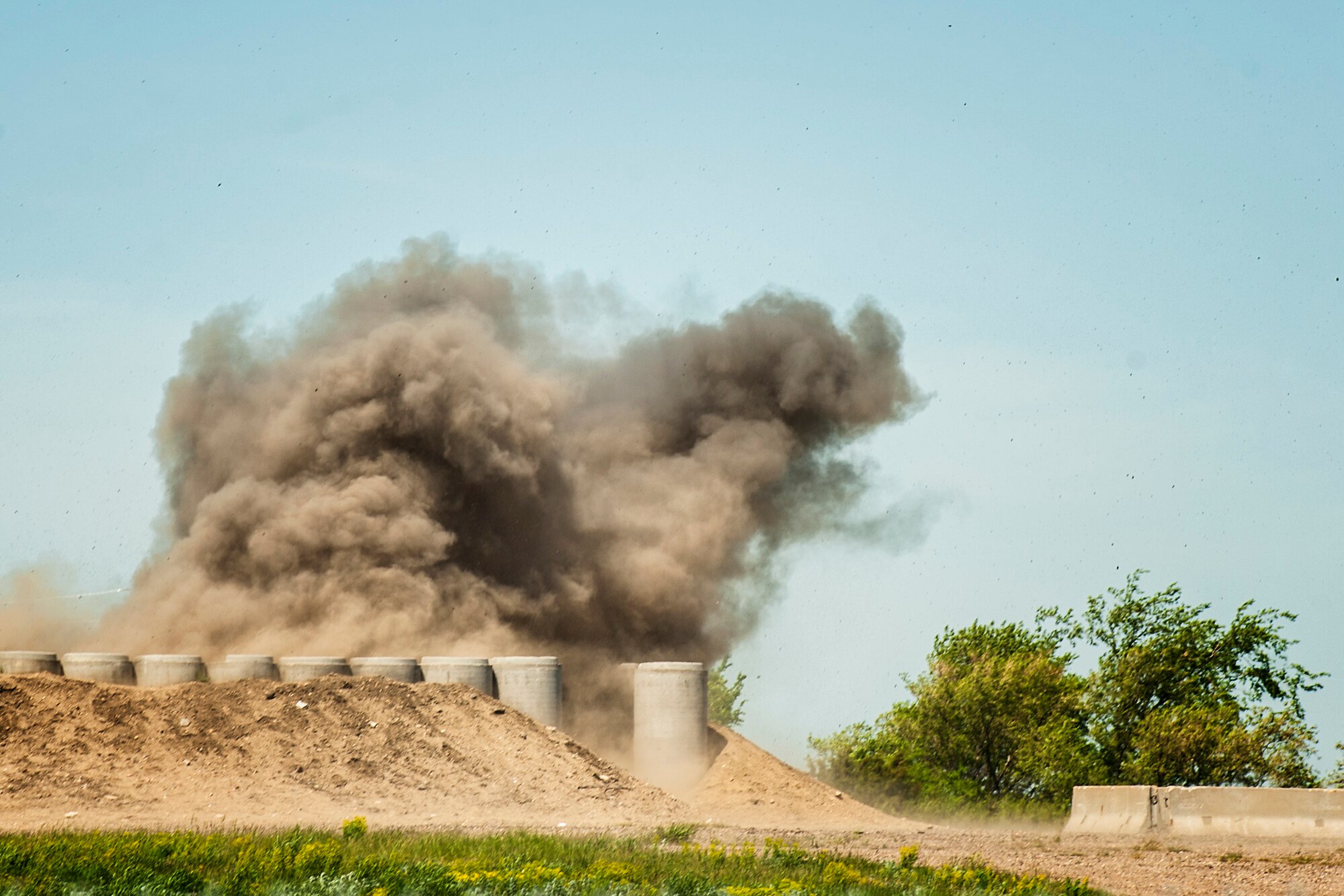 Smoke and dirt fly through the air after a controlled blast during an Expeditionary Training Day at Minot Air Force Base, N.D., June 1, 2017. The training included searching for and identifying simulated explosive ordinance to help prepare 5th Civil Engineer Squadron Airmen for future deployments. (U.S. Air Force photo/Senior Airman J.T. Armstrong)