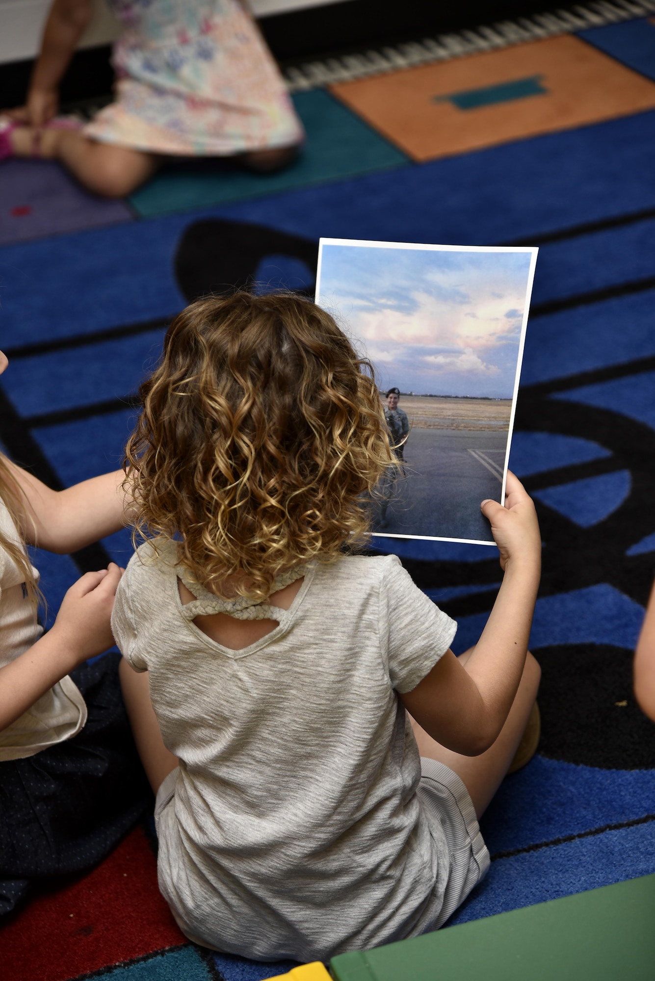 A pre-kindergarten student looks at a photograph of Air Force Staff Sgt. Miriam Y. Jarvis, 175th Force Support Squadron customer service NCO in charge, June 6, 2017, during a career day presentation at Oliver Beach Elementary School, Chase, Md. Jarvis was speaking to several classes about the Maryland Air National Guard and her role at the wing. (U.S. Air National Guard photo by Airman Sarah M. McClanahan /Released)