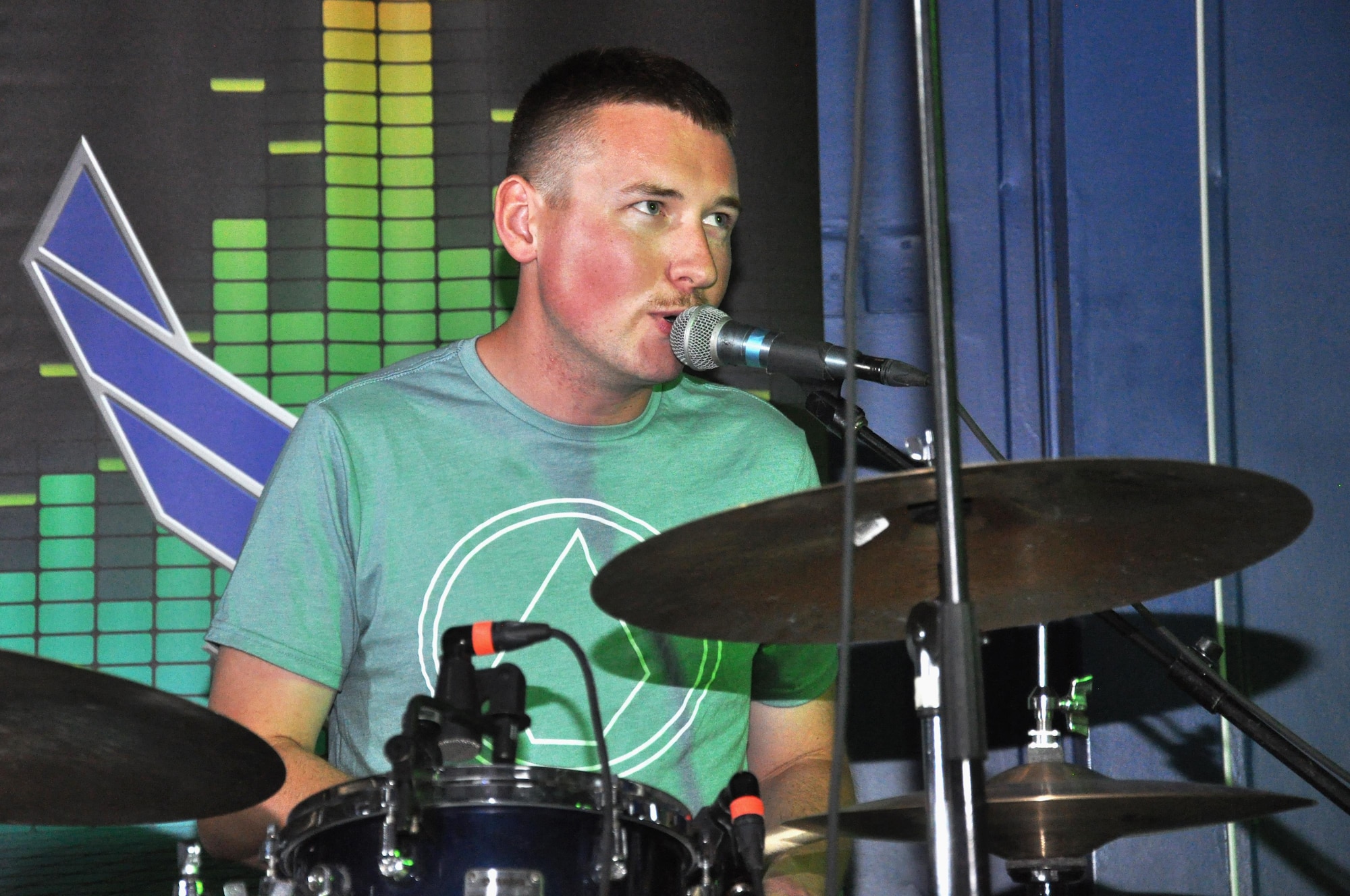 Airman 1st Class Joshua Dick, drummer and social media manager for the AFCENT Band, sings and drums during a song at the Starlifter Memorial Day concert Monday, May 29, 2017, at an undisclosed location in Southwest Asia. (U.S. Air Force photo/Master Sgt. Eric Sharman)