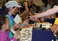 A child receives a dog tag during Operation Heroes at Minot Air Force Base, N.D., June 3, 2017. During the event, children tasted Meals Ready-to-Eat, tried on gear, saw weapons displays and created custom-made dog tags. The event concluded with a redeployment line and a welcome home celebration. (U.S. Air Force photo/Senior Airman Sahara L. Fales)