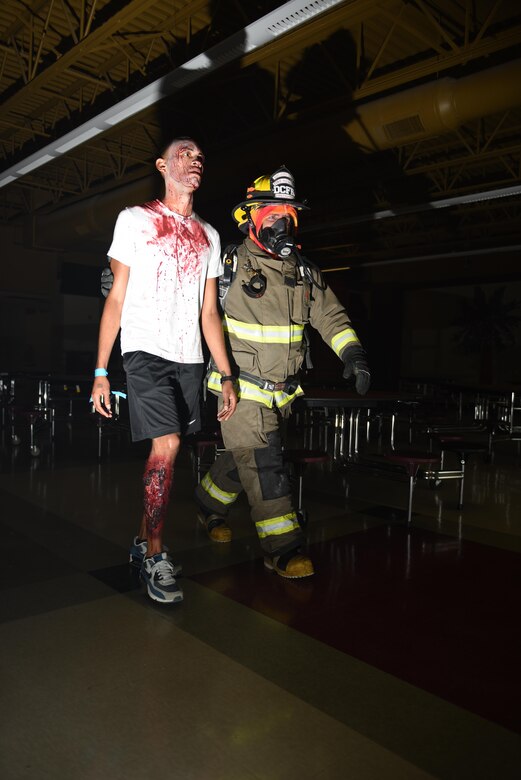 Michael Dopkant, Dorchester County Fire Department firefighter, escorts Staff Sgt. Christopher Basil, 628th Security Forces Squadron supply supervisor, from the cafeteria of Ashley Ridge High School during a mass casualty exercise in Summerville, S.C., June 6, 2017. Joint Base Charleston assisted multiple Dorchester County emergency response agencies during the community partnered exercise. The event aimed to improve interagency communication and response to large scale emergencies.