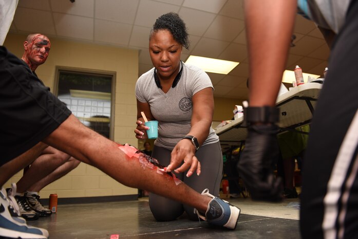 Master Sgt. Michelle Wilkes, 628th Medical Group medical information systems NCO in charge, applies cosmetics to a volunteer’s leg prior to Dorchester County’s mass casualty exercise at Ashley Ridge High School in Summerville, S.C., June 6, 2017. Joint Base Charleston assisted multiple Dorchester County emergency response agencies during the community partnered exercise. The event aimed to improve interagency communication and response to large scale emergencies.