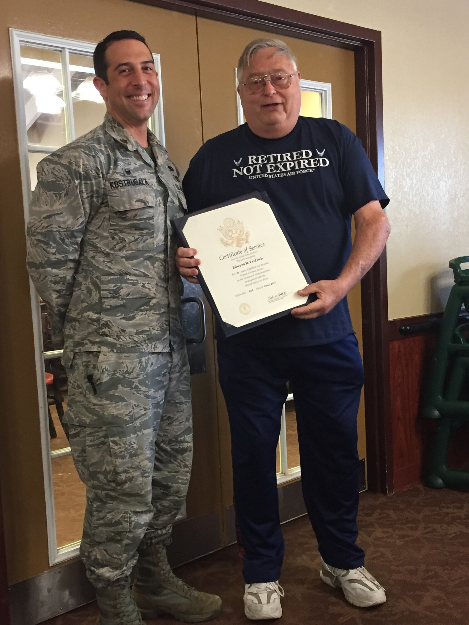 Edward “Fred” Fridrich displays the Certificate of Service he received at his retirement party. Friedrich is pictured with Maj. Kazimir Kostrubala, 375th Logistics Readiness Squadron commander.