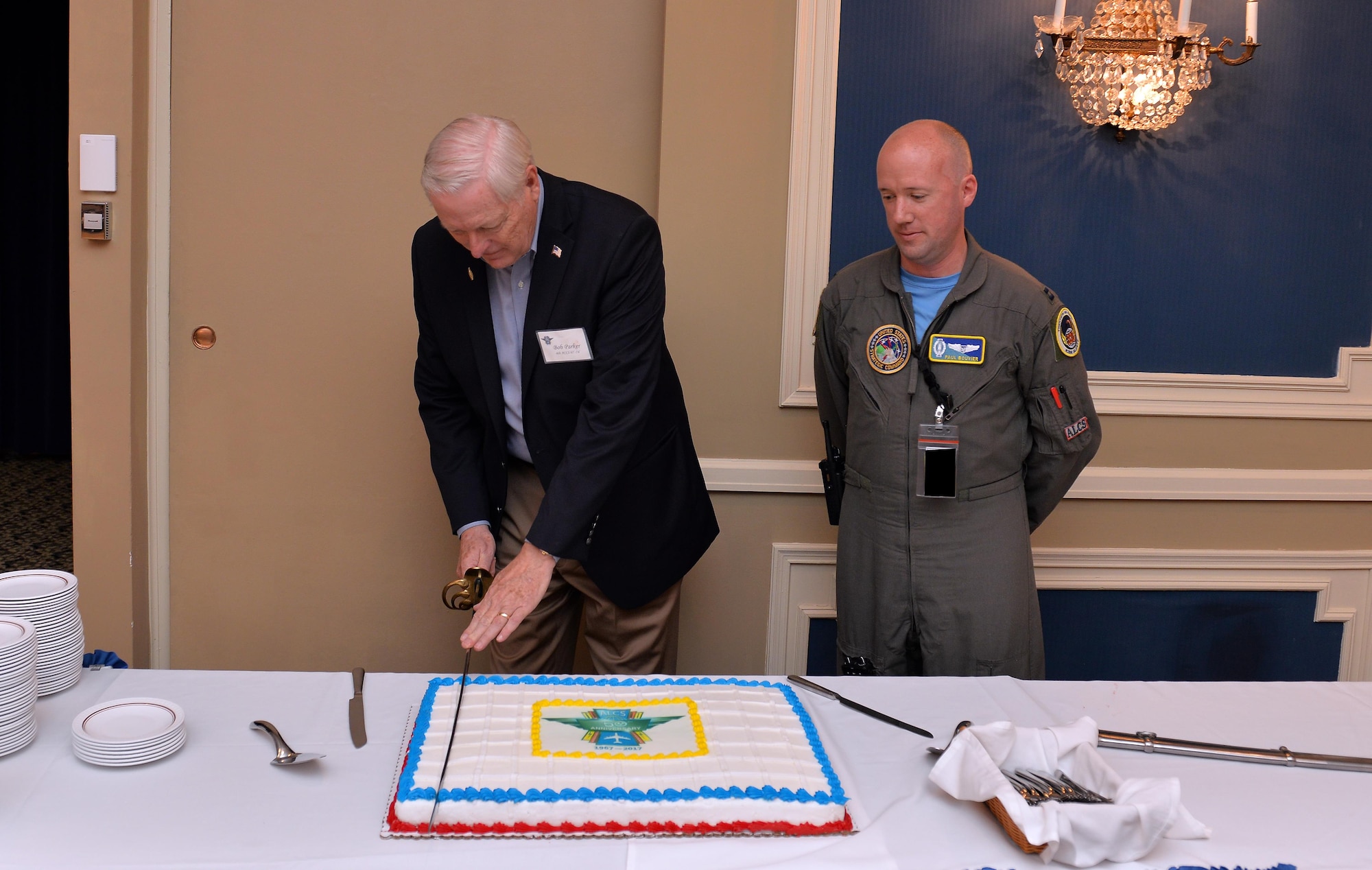 Retired Maj. Gen. Robert Parker, the first commander to lead the Airborne Launch Control System in 1967, ceremoniously cuts the anniversary cake with a saber alongside Capt. Paul Bouvier, a missileer assigned to the 625th Strategic Operations Squadron, at the 50th Anniversary celebration held June 2. the Patriot Club, Offutt Air Force Base, Neb. Over 80 Airmen both active duty and retired attended the event to celebrate the 50th anniversary of the Airborne Launch Control System. (U.S. Air Force photo by Josh Plueger)