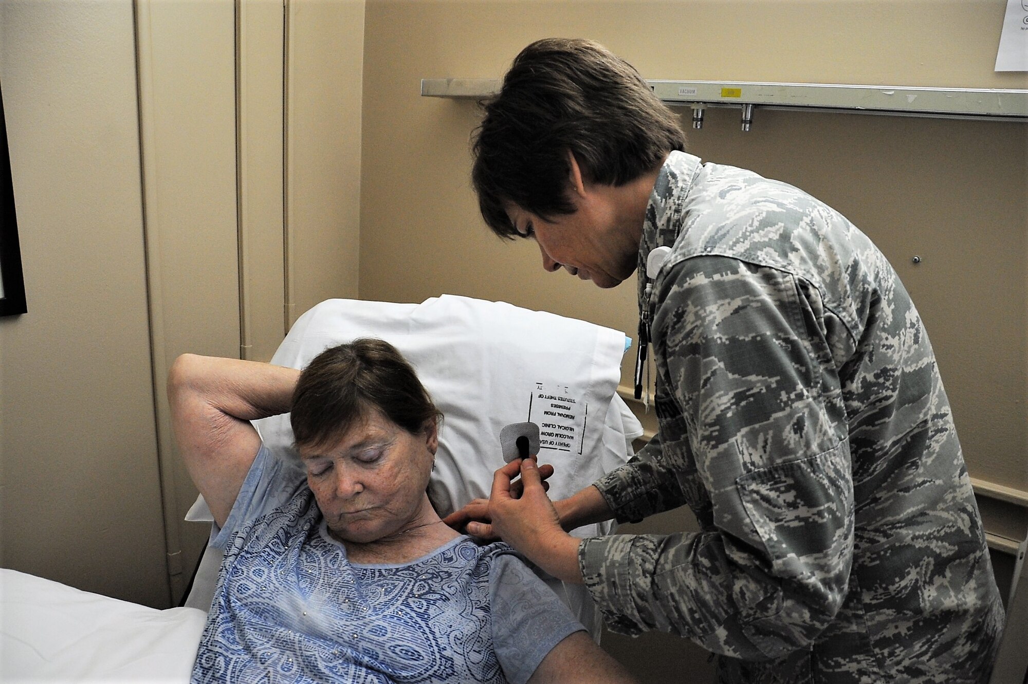 Lt. Col Candy Wilson (right), 779th Medical Group nurse practitioner, places a Nerve Scrambler electrode inches away from the source of nerve pain on the back of a patient’s neck May 30, 2017 at Joint Base Andrews, Md. Another electrode will be placed on the patient’s foot where she feels no pain. The low electrical current that passes through the electrodes to Grays body causes a “no pain” signal to override the existing pain signal being sent to the patient’s brain. (U.S. Air Force photo by Staff Sgt. Joe Yanik)
