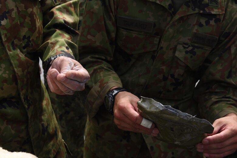 Members of the Japan Ground Self-defense Force interact with a glove and powder used by the 1-1 Air Defense Artillery battalion during chemical, biological, radiological and nuclear defense decontamination exercises, May 18, 2017, at Kadena Air Base, Japan. 1-1 ADA members hosted JGSDF and members of the 18th Wing, demonstrating CBRN decontamination practices on the Patriot missile system. (U.S. Air Force photo by Senior Airman Nick Emerick)