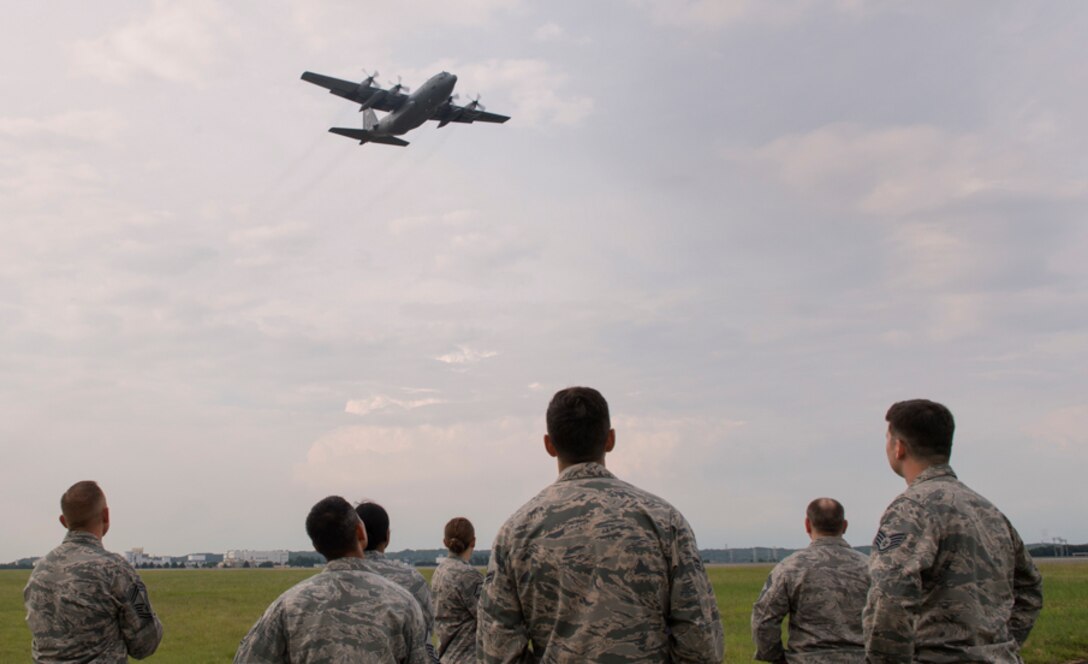 Members with the 374th Civil Engineer Squadron look up at a C-130 Hercules flying over the flightline during an annual certification test of the Aircraft Arresting System at Yokota Air Base, Japan, June 1, 2017. Airmen from the 374 CES and 374th Operations Support Squadron are responsible for setting up the system and logging any deficiencies during the test. (U.S. Air Force photo by Yasuo Osakabe)