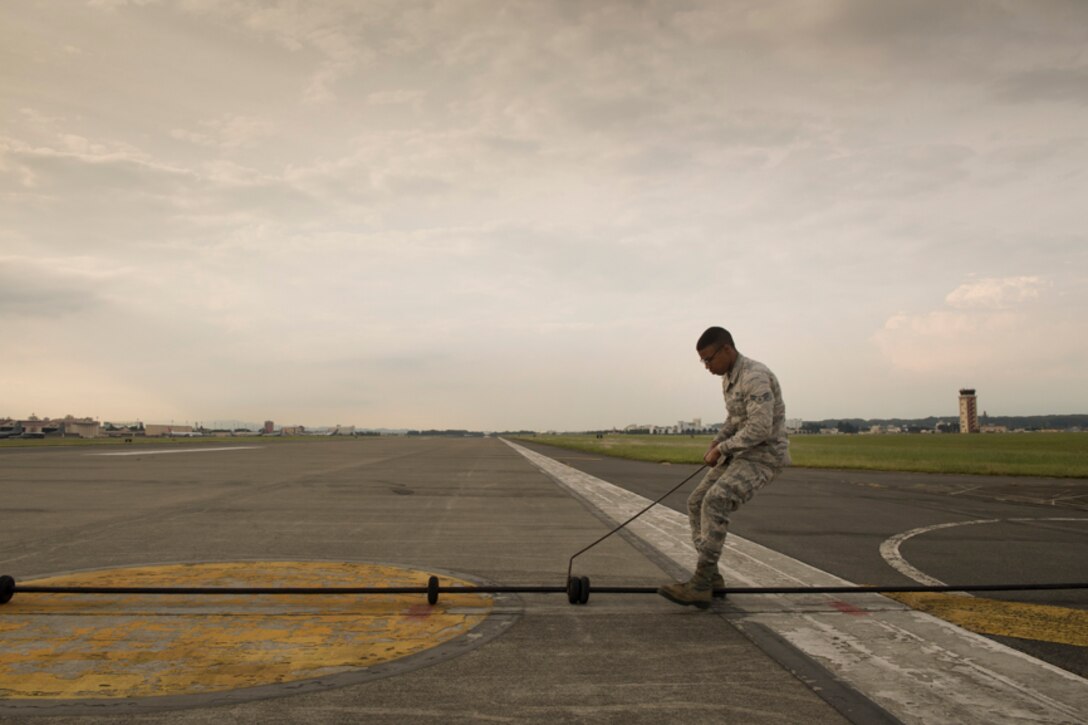 Airman 1st Class Alijah Norris, 374th Civil Engineer Squadron power production technician, aligns pendant support disks at Yokota Air Base, Japan, during an annual certification test, June 1, 2017. The Aircraft Arresting System is a barrier used to catch the arresting hook on fighter aircraft in case of malfunction upon landing or take off. (U.S. Air Force photo by Yasuo Osakabe)