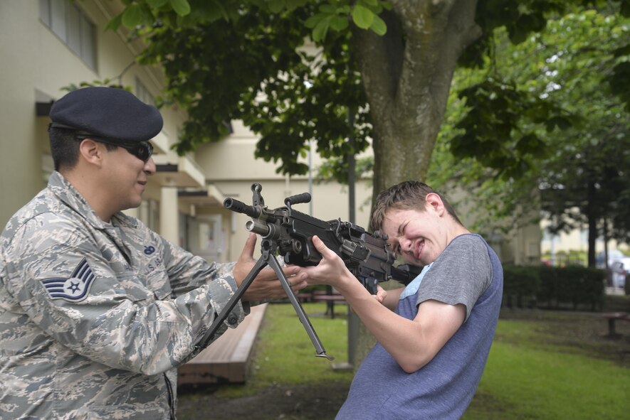 U.S. Air Force Staff Sgt. Eric Ramon, a 35th Security Forces Squadron combat arms instructor, assists a young man with holding a M249 light machine gun during a security forces immersion with kids from the teen and youth centers at Misawa Air Base, Japan, June 8, 2017. The event was part of a national project with the Boys and Girls Club of America and the first time it occurred at Misawa. (U.S. Air Force photo by Capt. Samantha Morrison)